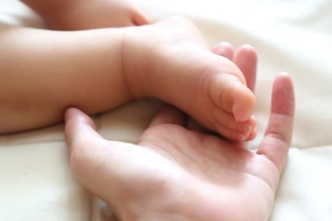 赤ちゃんの足を握るママの手