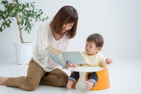 赤ちゃんに絵本を読む保育士