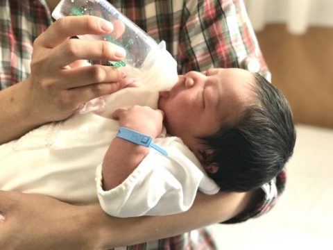 哺乳瓶でママはミルクを飲ませる新生児
