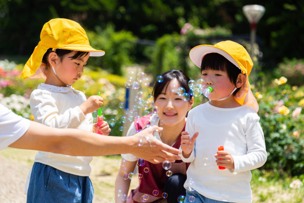 子供とシャボン玉をする保育士