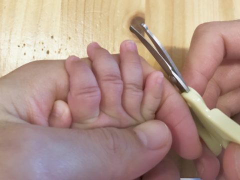 赤ちゃんの爪をハサミで切る